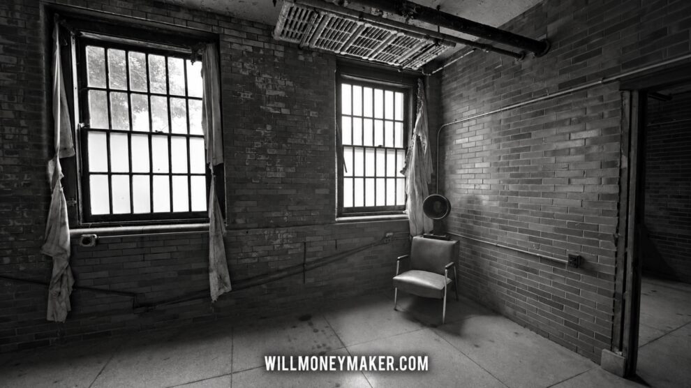 Black-and-white photograph of an abandoned room with tall windows, a chair, and a fan.