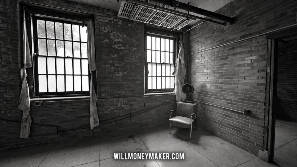 Black-and-white photograph of an abandoned room with tall windows, a chair, and a fan.