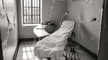 Black-and-white photograph of an empty chair beside a window in a worn room.