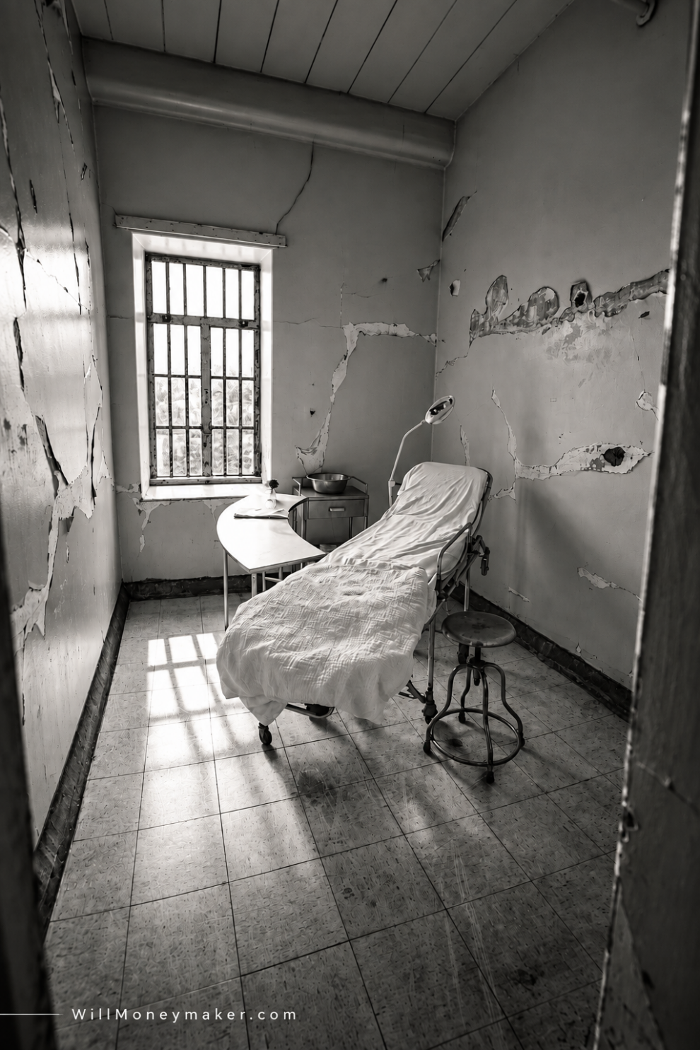 Black-and-white photograph of an empty chair beside a window in a worn room.